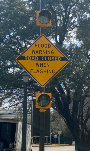 siamond shaped yellow sign with black letters and flashing light above and below the sign