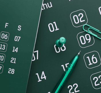 Calendar on a green background with a pen and a push pin