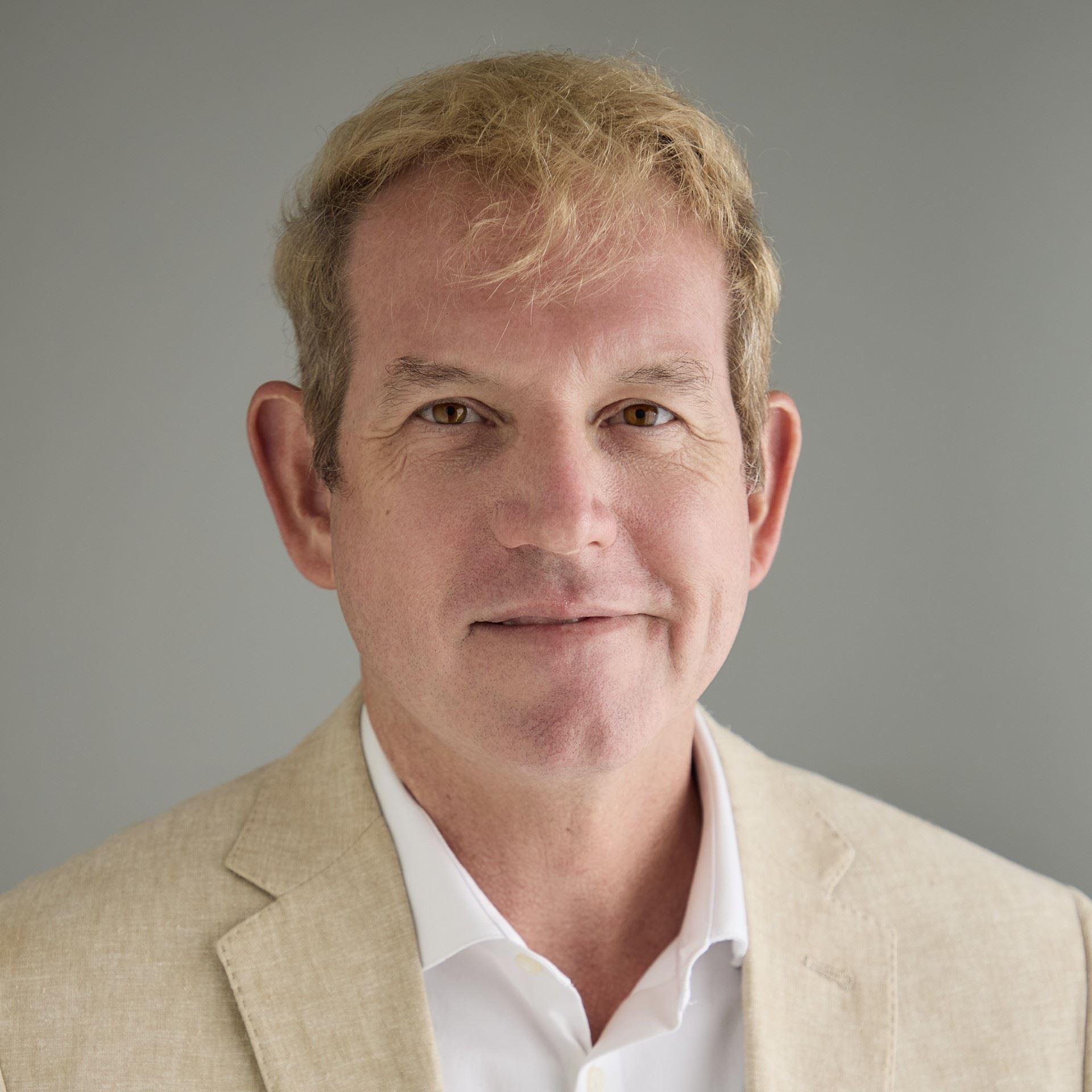 Man with blonde hair, white dress shirt and tan suit jacket