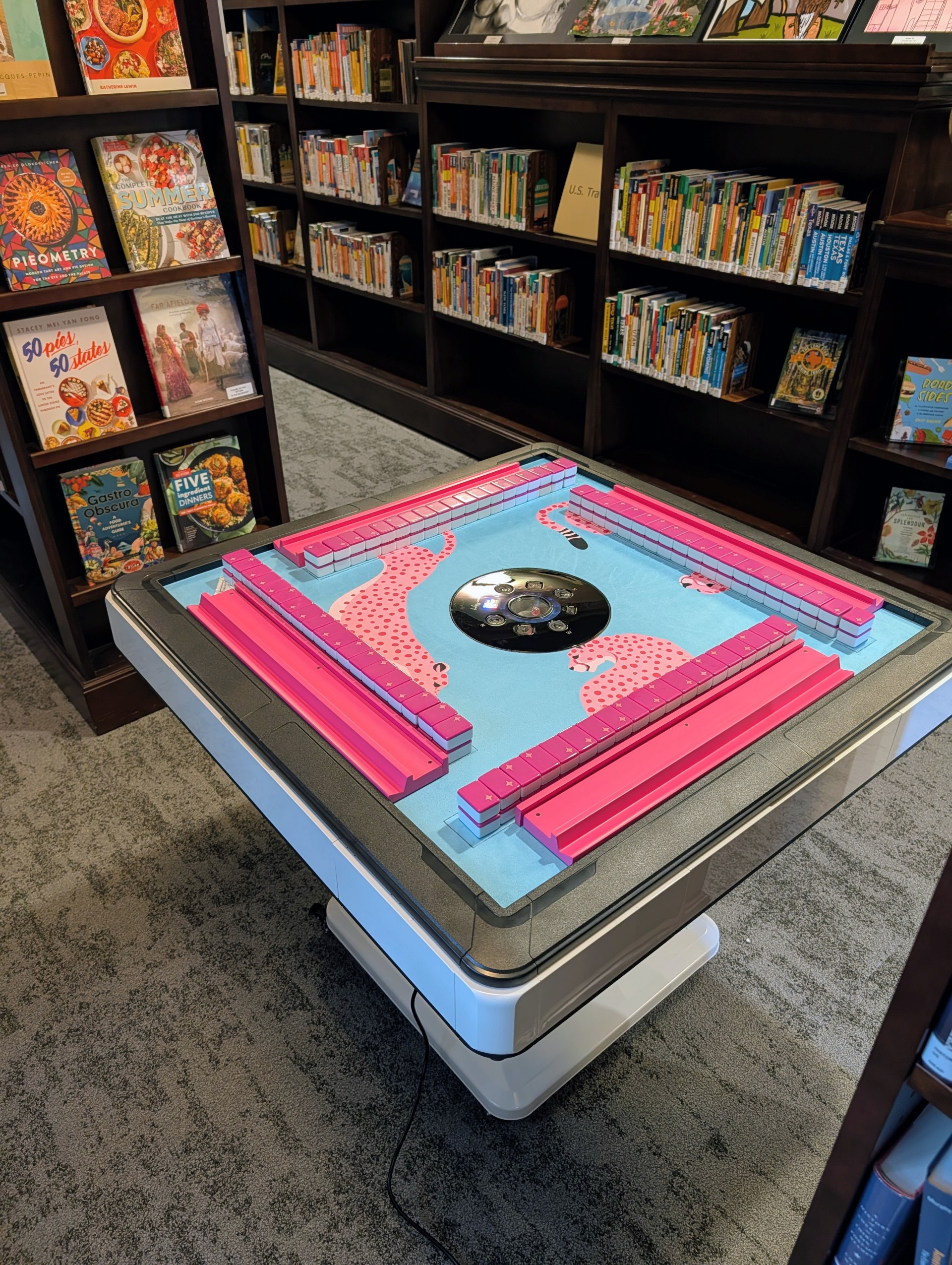A mahjong table with tiles and a blue mat with pink leopards